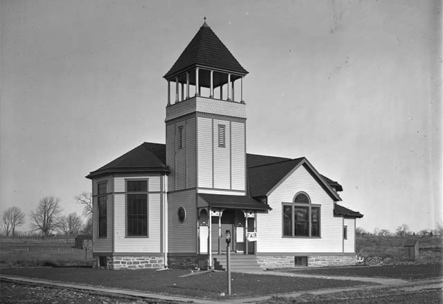 small white church surrounded by open land