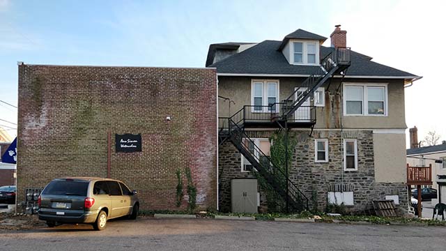 side view a house with a boxy brick retail extension on the streetfront