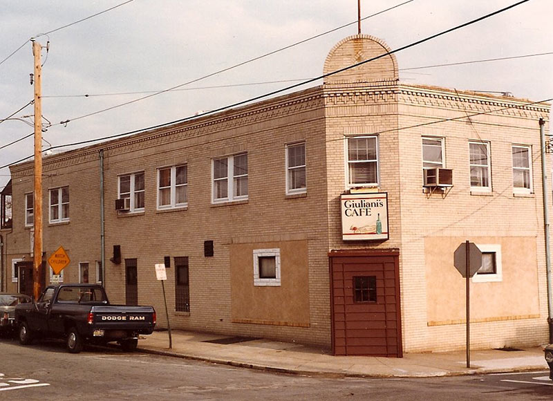 2-story beige-brick buiding with rounded pediment over corner