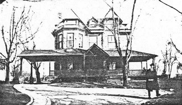 large 3-story frame house with port-cochere, man standing in driveway in front