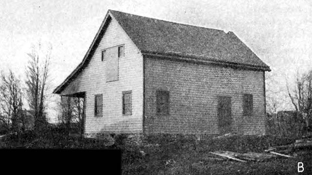 2-story plain wood building, with covered porch in rear