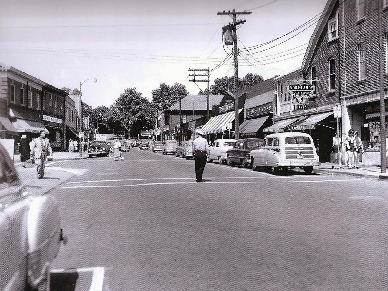 policeman stands on the crosswalk on Haverford Ave. while girls in bobby sox cross.
