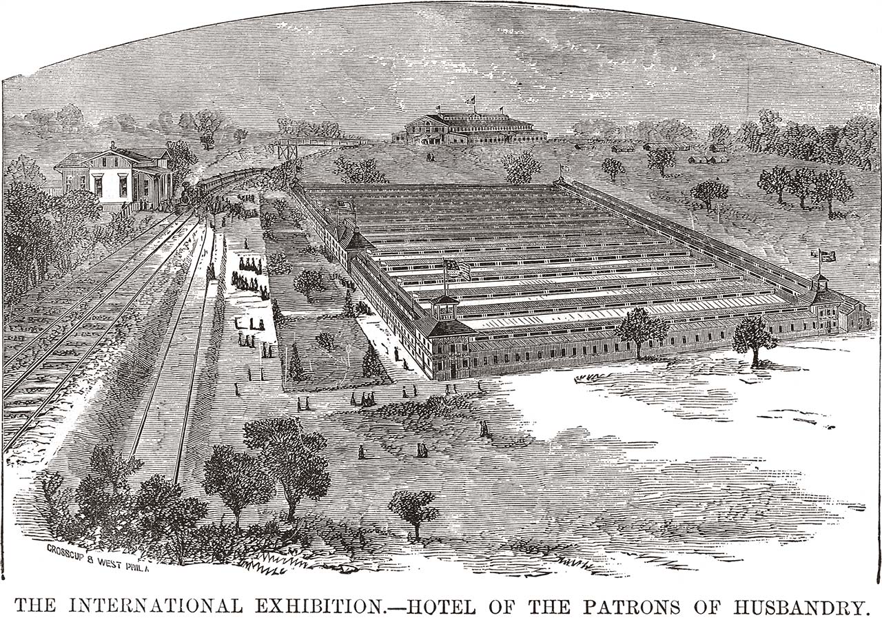 overhead view of large building, train tracks and station to left