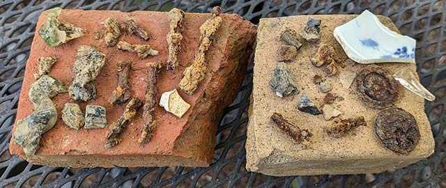 rusty nails and melted glass laid out on two bricks