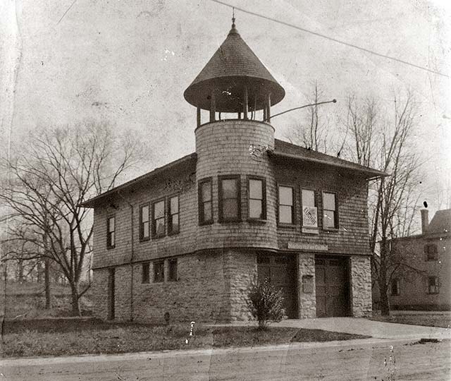 firehouse with watchtower stands almost alone on an unpaved street in a winter landscape