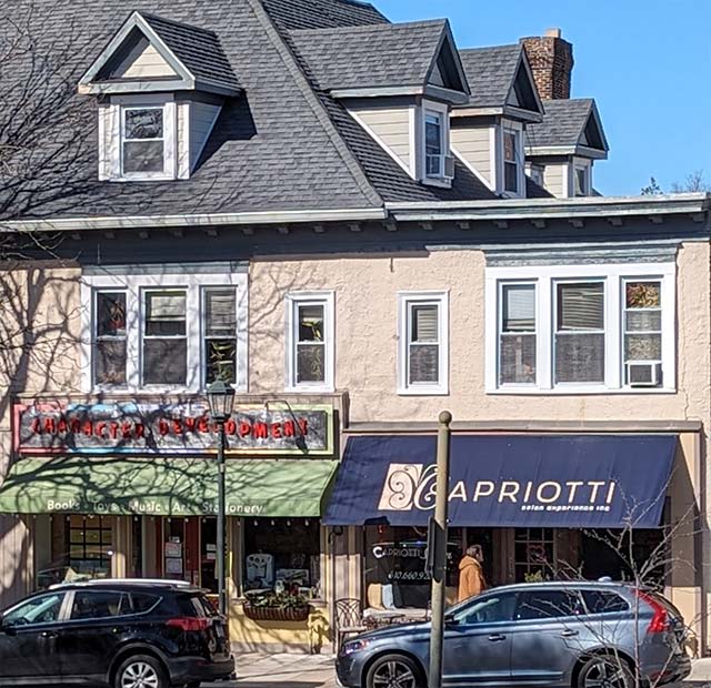 color photo of same building in 2024; 2 storefronts have replaced arcade entrance