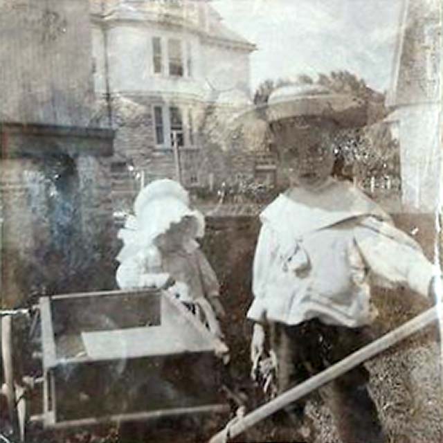 young boy plays with a wagon and a toddler in a bonnet