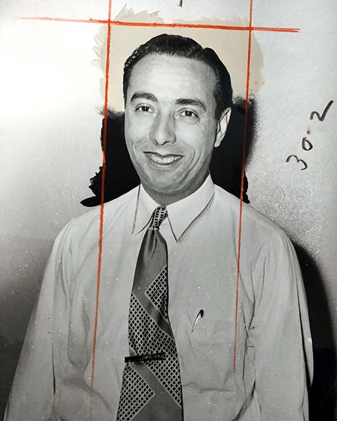 smiling young man wearing white shirt, long tie with a tiepin, pen in breast pocket