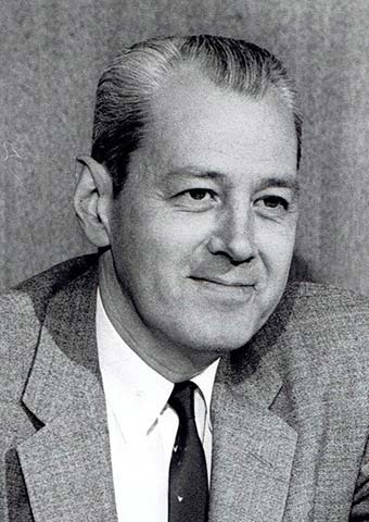 head and shoulders smiling middle aged man with crewcut in a suit