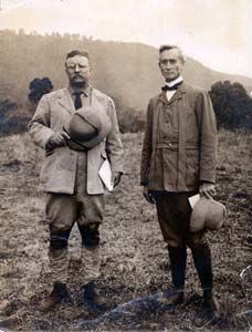 2 men holding pith helmets pose outdoors; Theodore Roosevelt in on the left