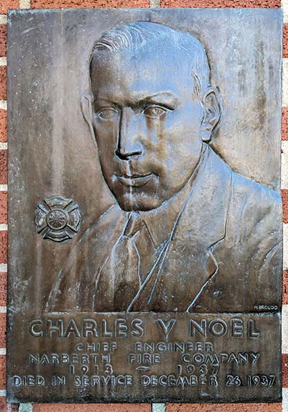 bronze plaque with bas-relief head and shoulders portrait of a determined-looking man, seal of the Narberth Fire department to his left