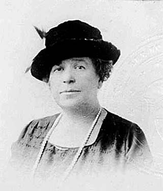 portrait of middle aged woman wearing a feathereed cap and pearl necklace
