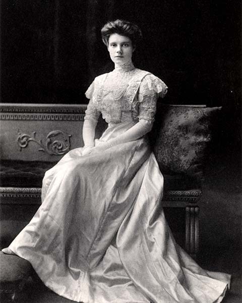 young woman poses in heer long white wedding dress