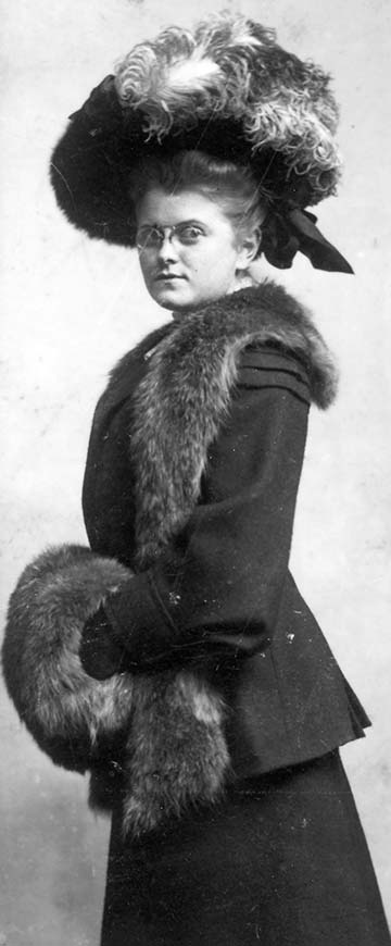 formal full-length portrait of spectacled lady in ostrich plumes, fur muff and shawl
