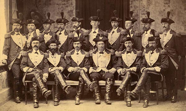 16 uniformed men pose in two rows