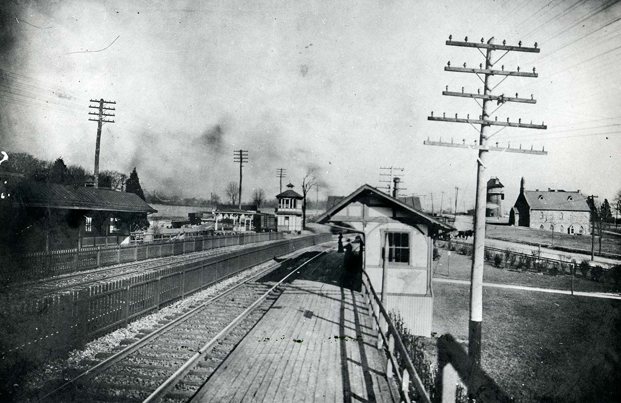 trains tracks facing inbound; Baptist church and water tower on right