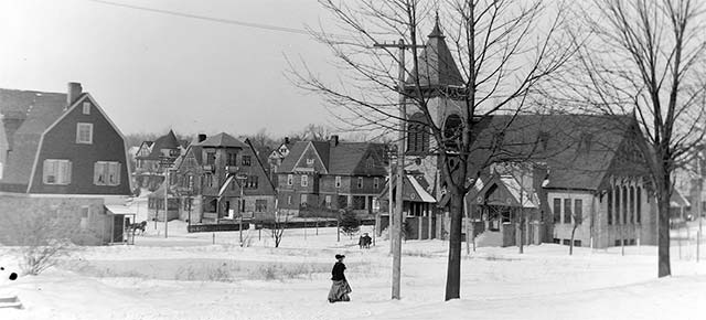 winter scene in early Narberth: snow on ground, woman in elaborate coat and hat, horse-drawn carriage, church and houses